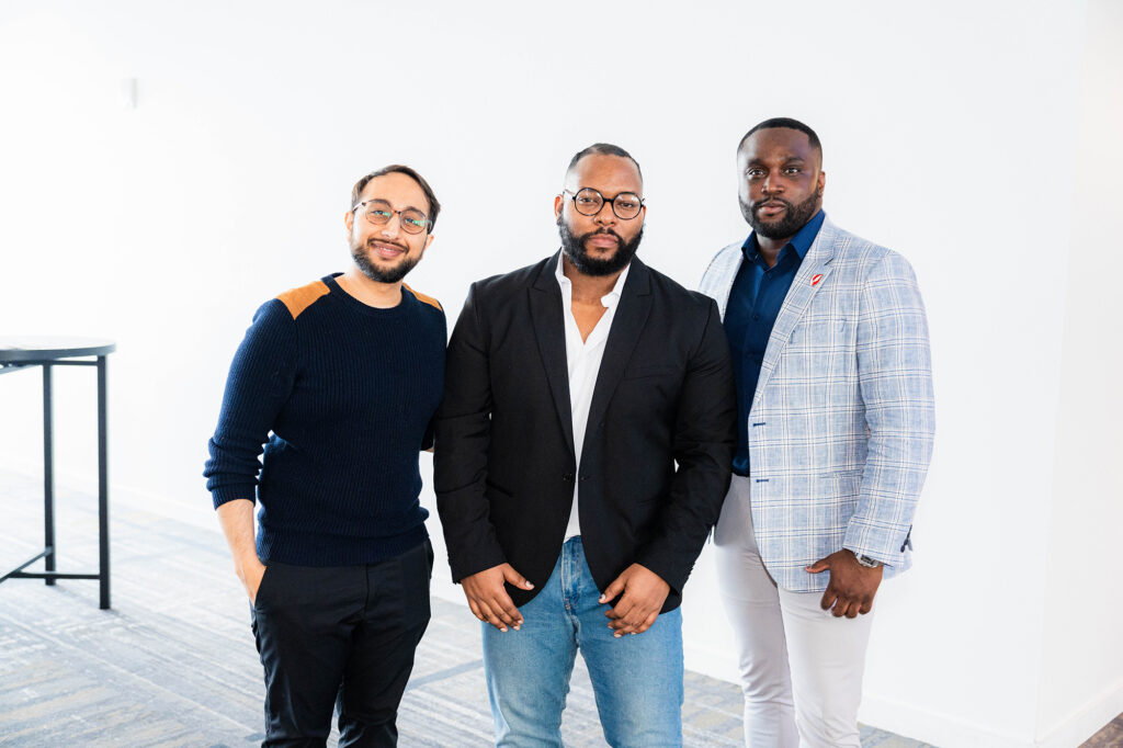 Three men pose at the. Biomedical H.I.V. Summit