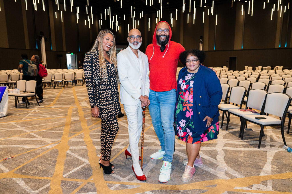 Four people pose in front of the speaker hall.